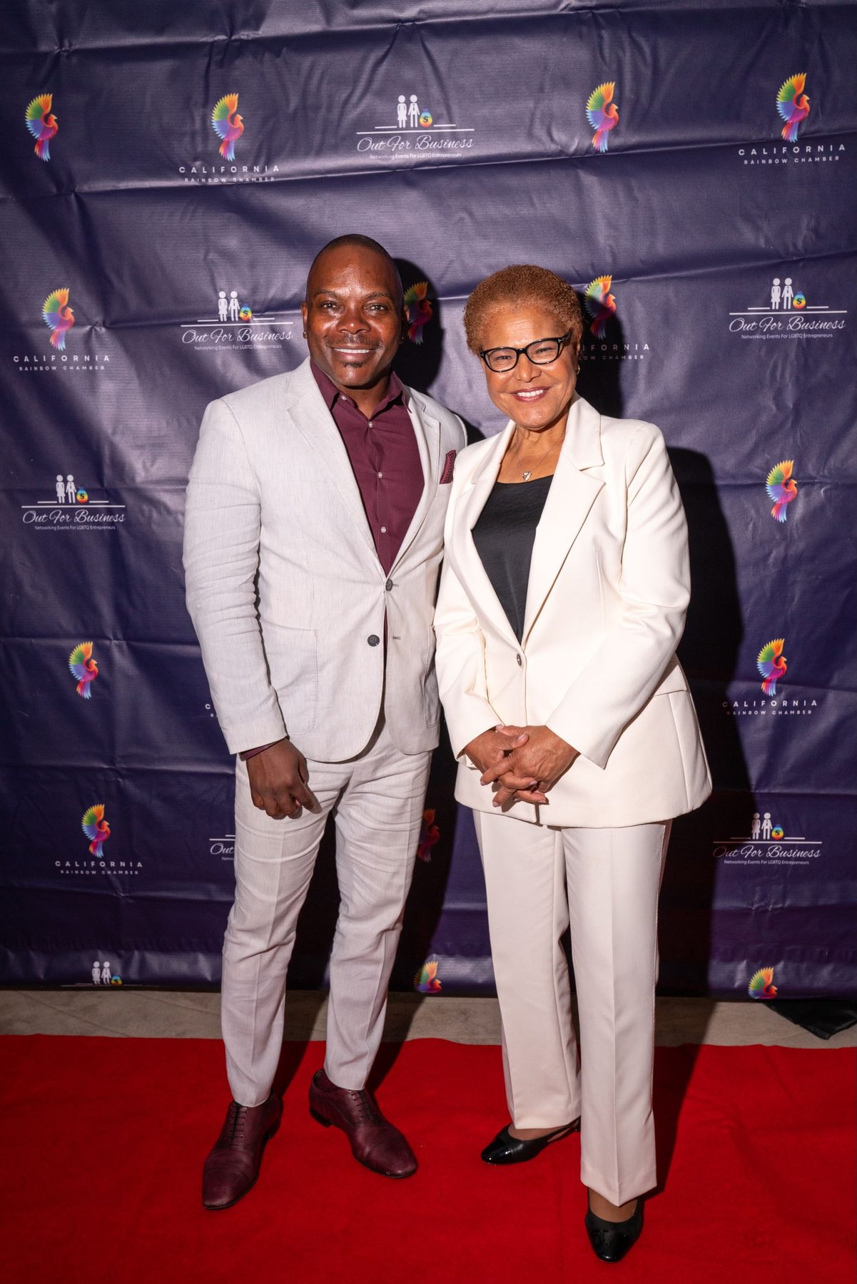 Two attendees on the red carpet in front of the Out for Business backdrop