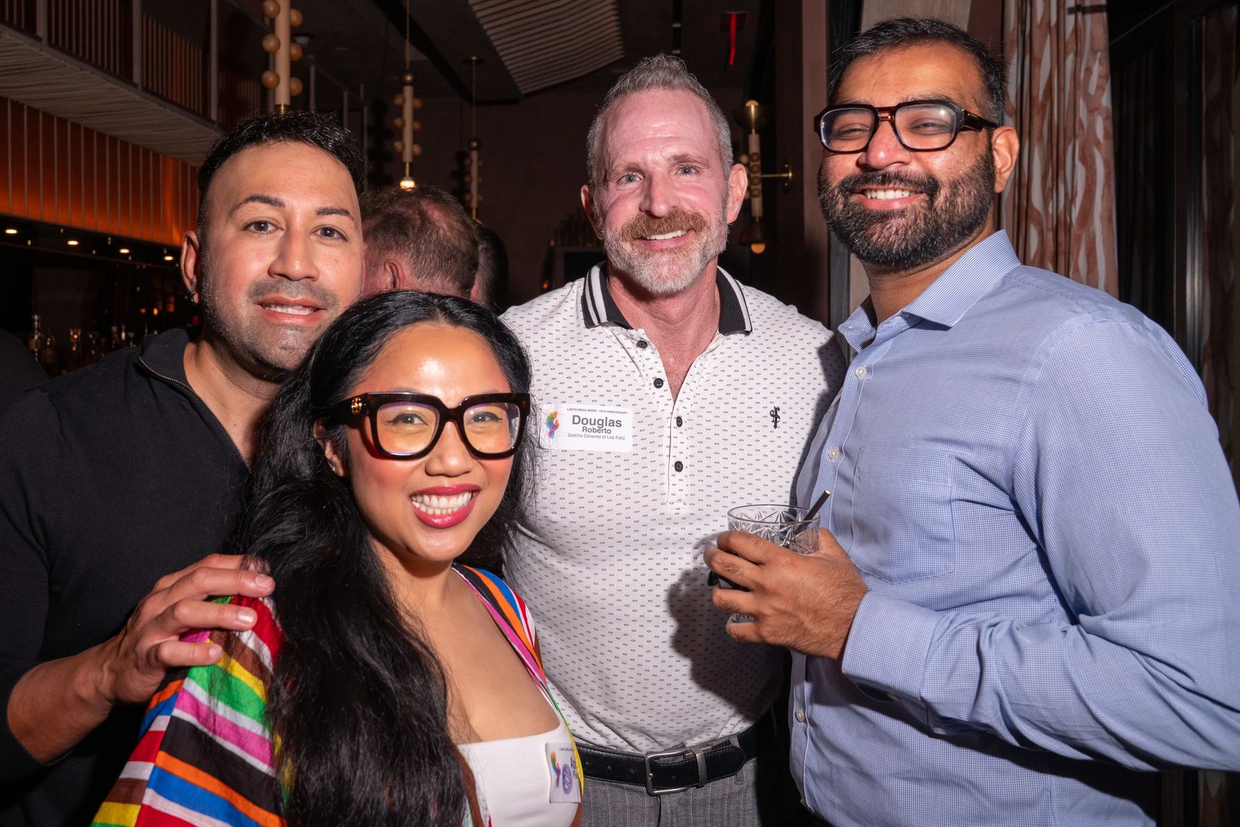 Four attendees posing together by the bar