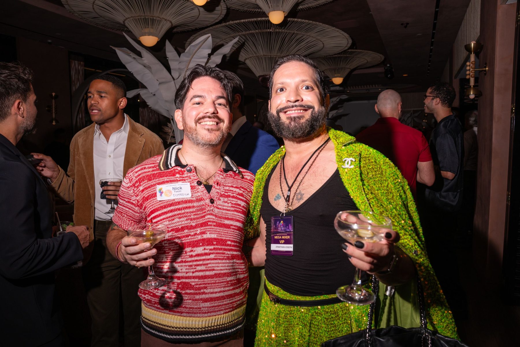 Two attendees with cocktails, one wearing a VIP lanyard
