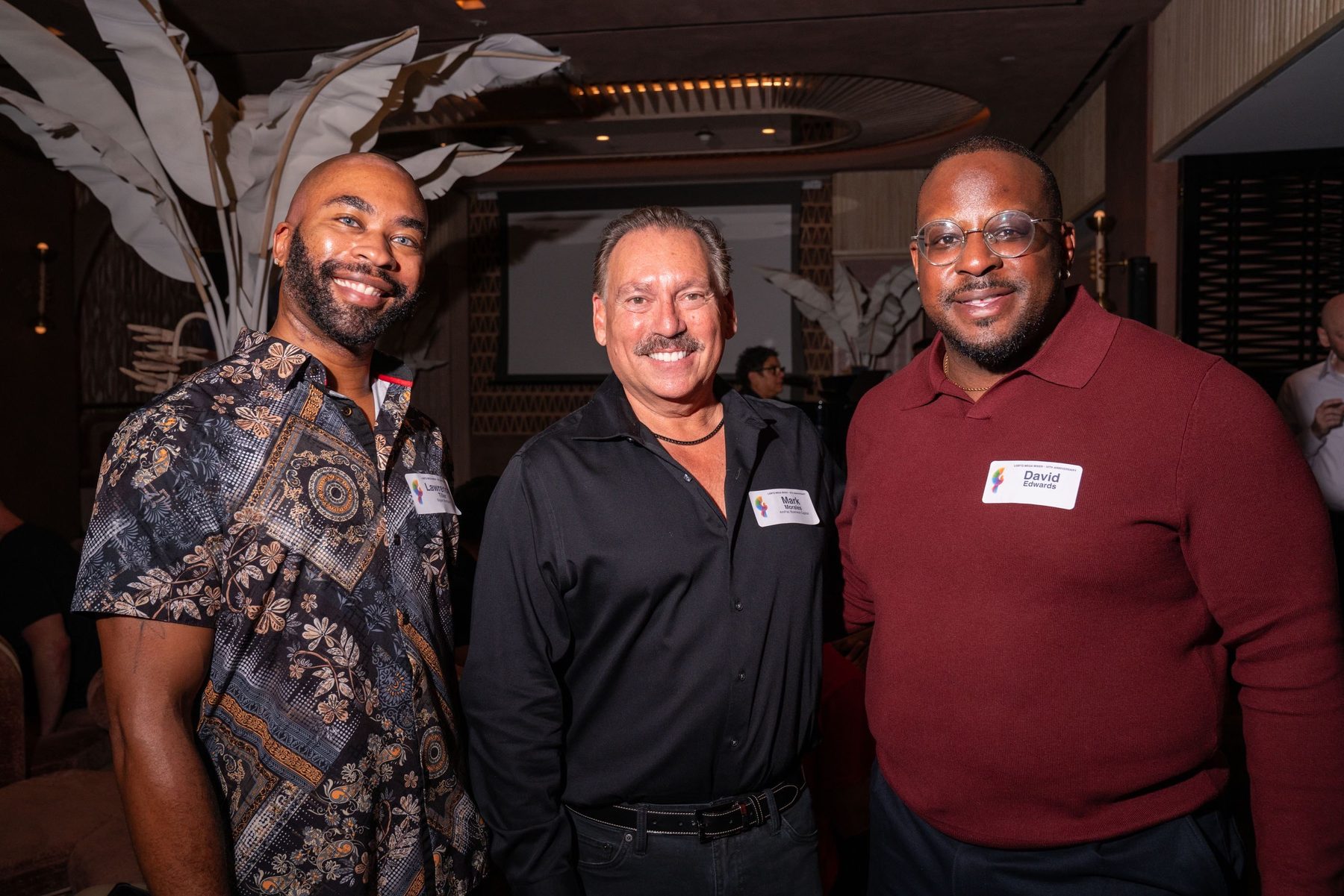 Three attendees posing together under the lounge lighting
