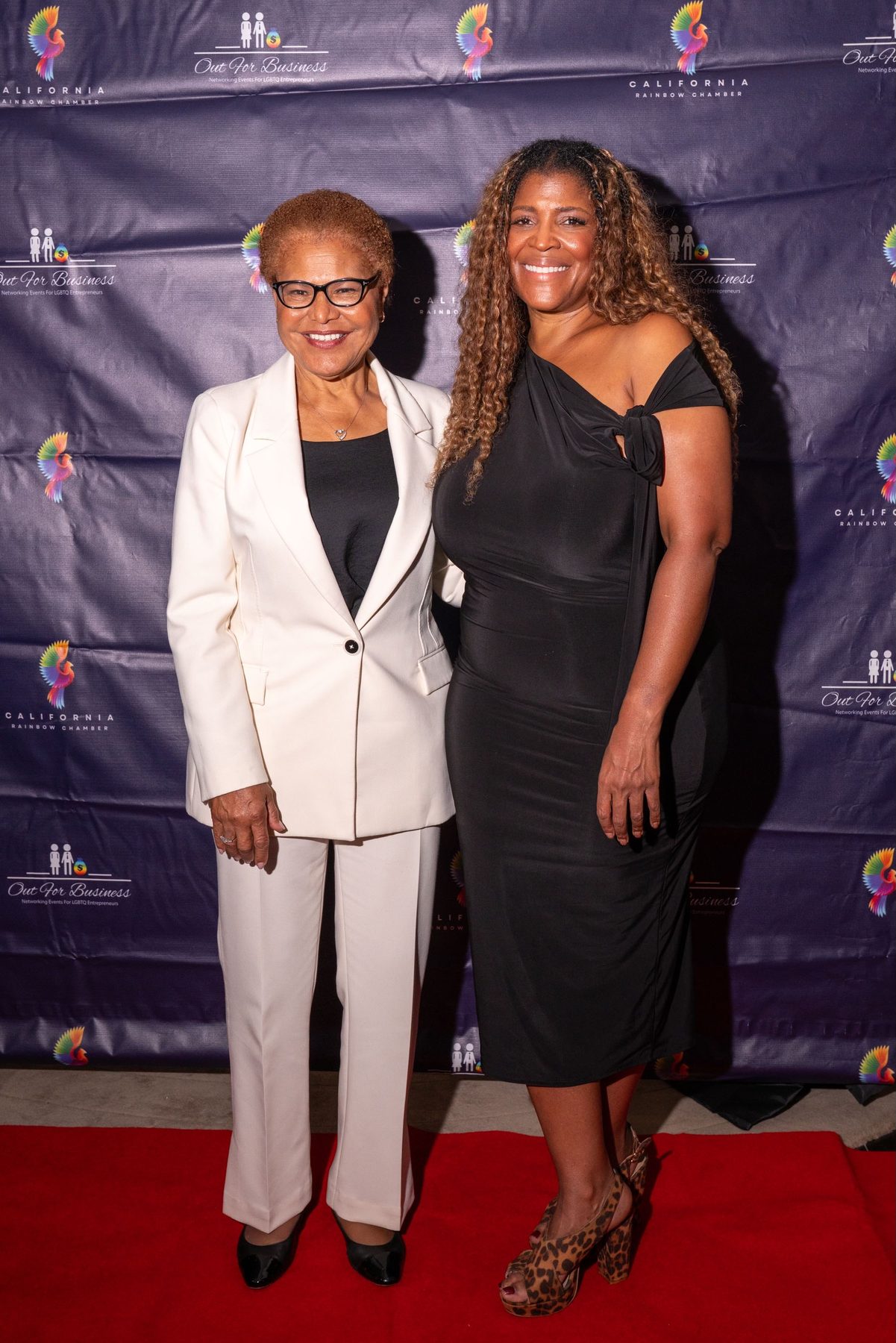 Two attendees standing full length on the red carpet in front of the Chamber backdrop