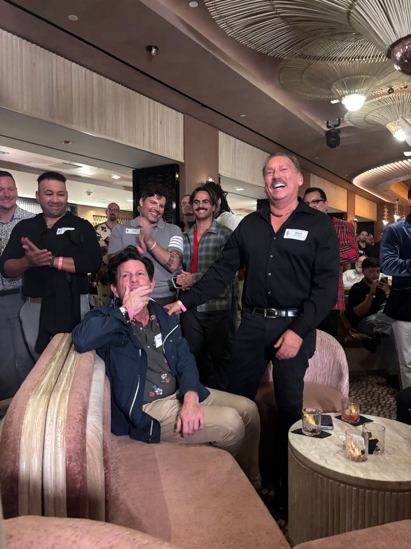 Attendees applauding around a seated guest in the lounge